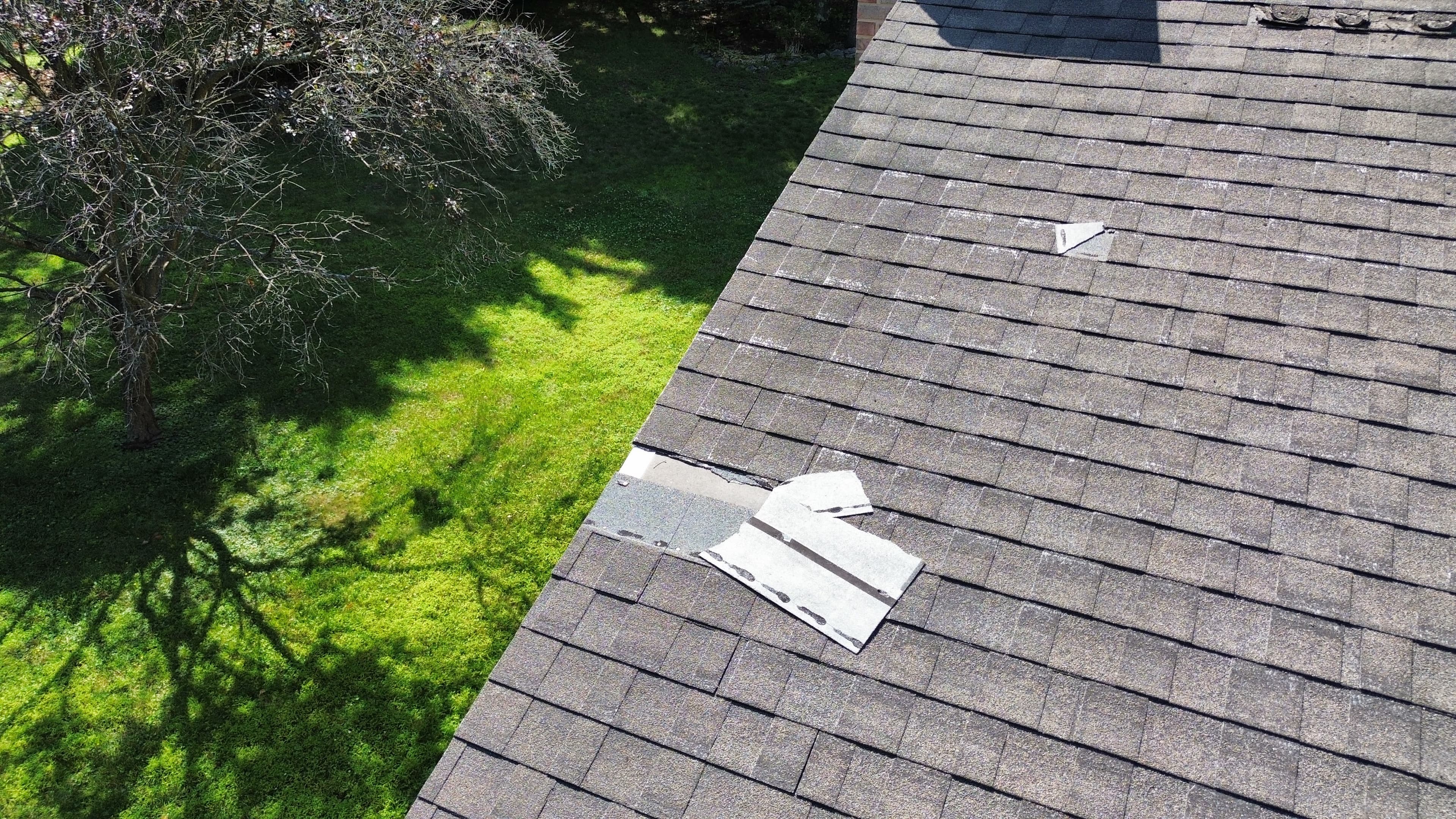 Missing and damaged roof shingles, photographed from a drone during a real FLOW inspection